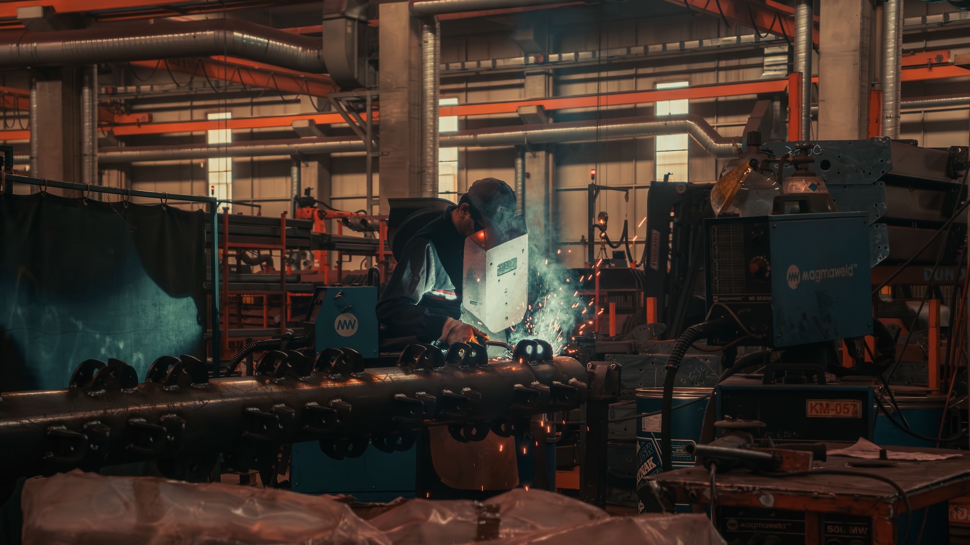 Steel fabricator cutting metal, sparks flying in a dark workshop